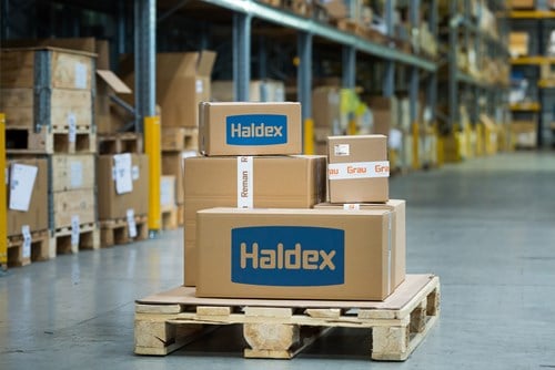 Stacked Haldex-labeled boxes sit on a wooden pallet in a large warehouse aisle