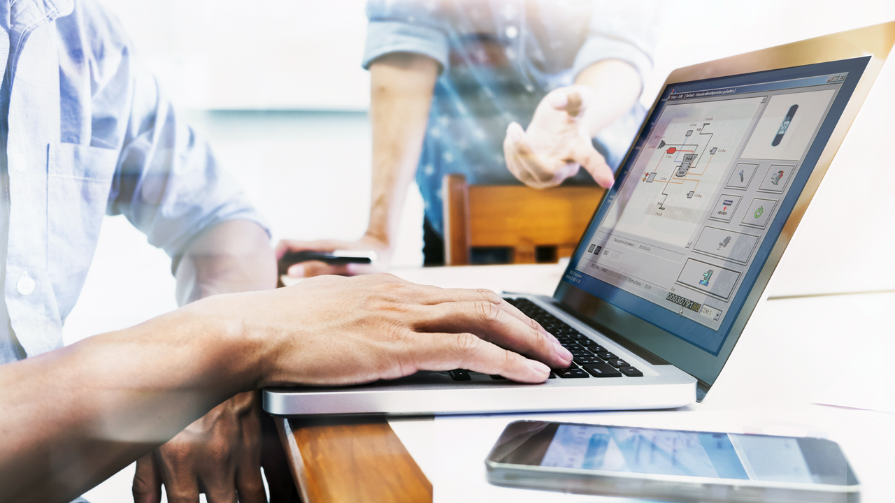 Hand writing on a laptop showing schematics