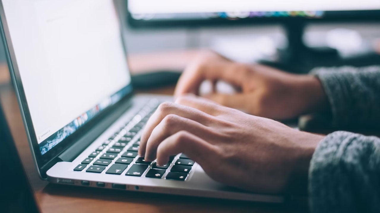 Hands writing on a laptop